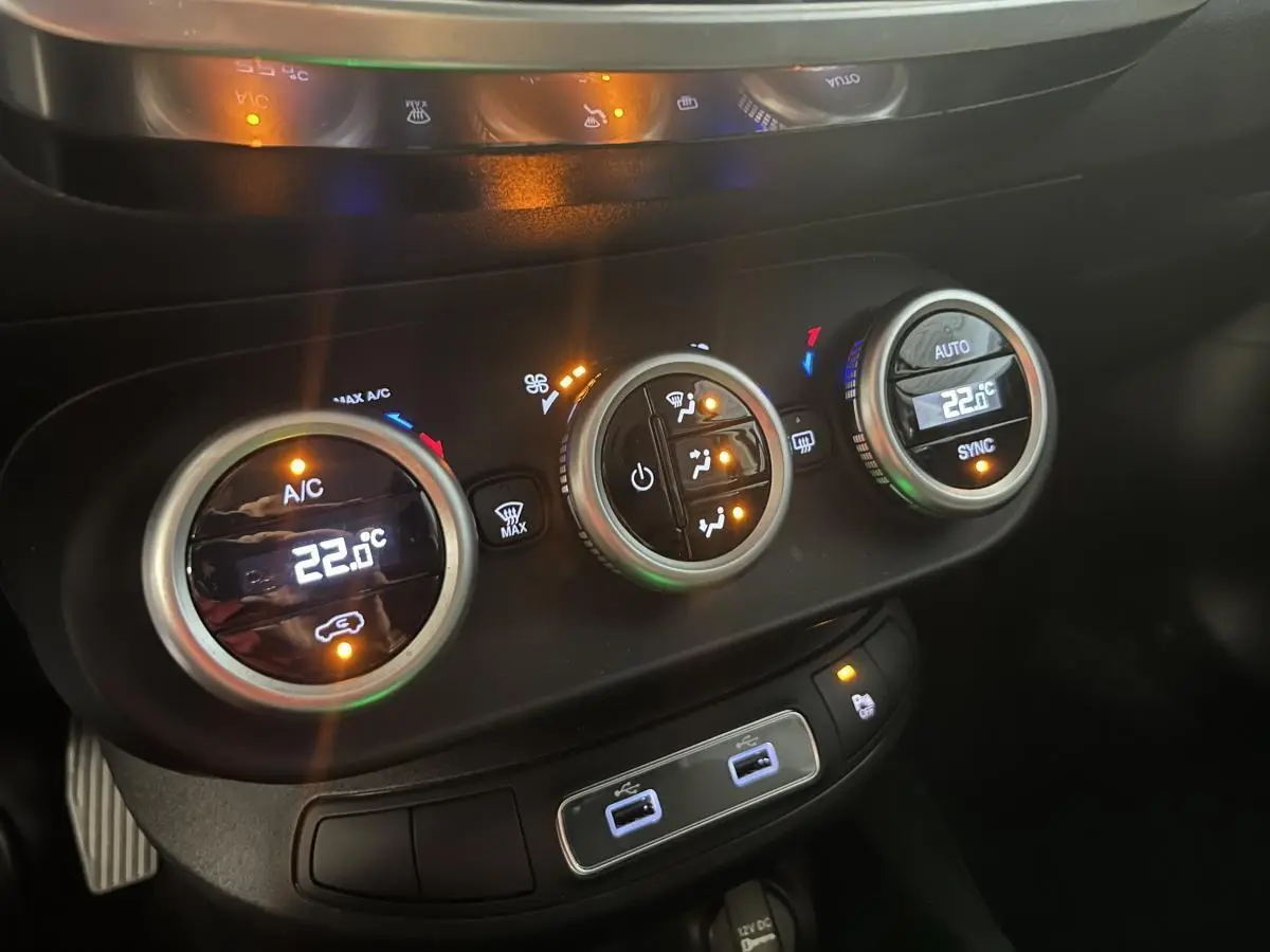 Gros plan sur la console centrale du Fiat 500X 2024 montrant les commandes de climatisation automatique bi-zone et ports USB.