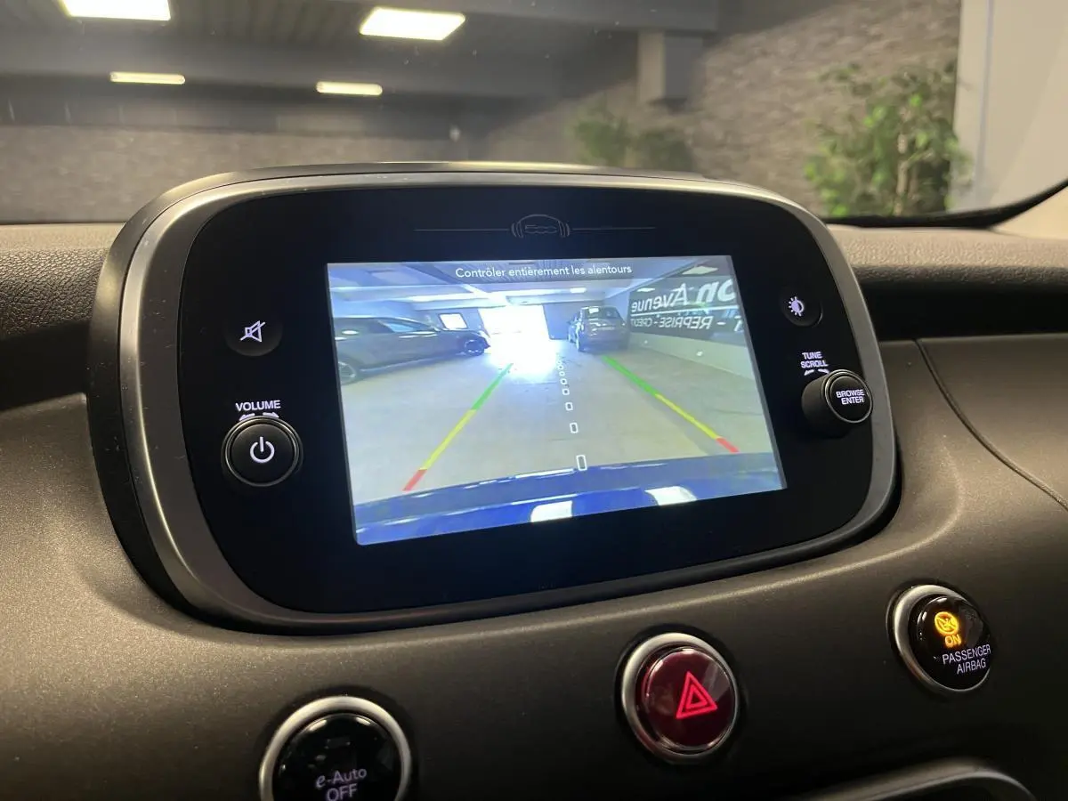 Écran multimédia affichant la caméra de recul d'une Fiat 500X bleu, vue intérieure du tableau de bord.