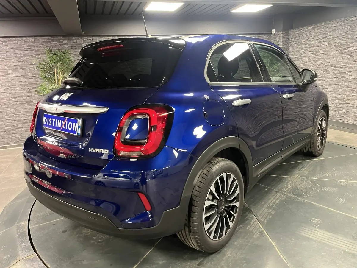 Fiat 500X bleu métallisé vue 3/4 arrière droit, jantes alliage 17 pouces et vitres surteintées.