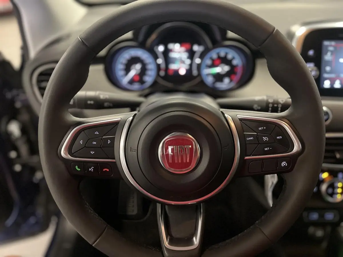 Volant Fiat 500X 2024 en cuir noir avec commandes intégrées, cadrans lumineux et tableau de bord gris titane.