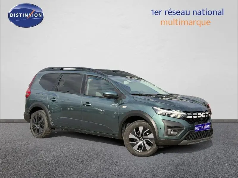 Vue 3/4 avant droit du Dacia Jogger 2025 vert cèdre métallisé avec jantes noires et toit noir contrasté.