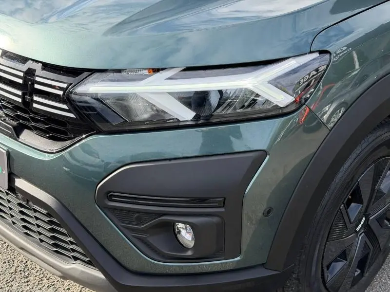 Gros plan sur l'avant droit du Dacia Jogger 2025 en Vert Cèdre métallisé, mettant en valeur son phare LED et la calandre noire.