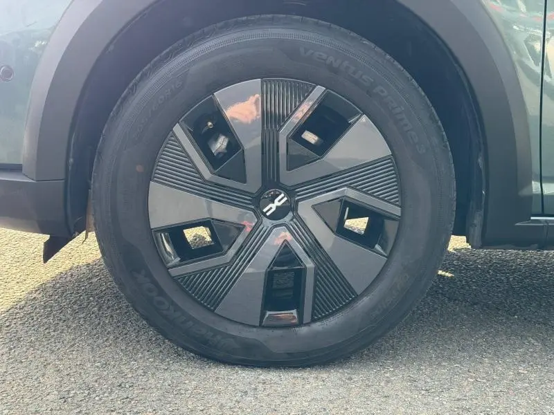 Gros plan sur la roue avant gauche du Dacia Jogger Vert Cèdre métallisé avec jante noire et détails géométriques.