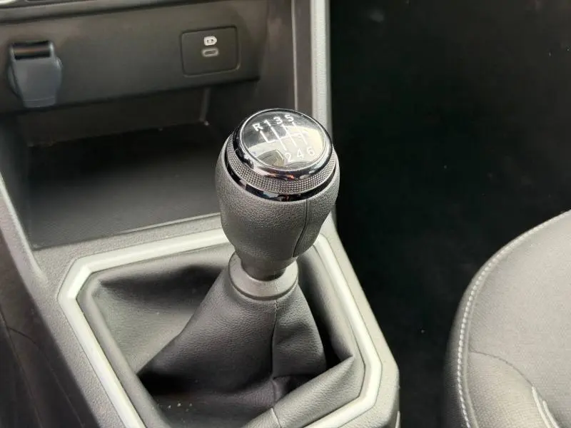 Gros plan sur le levier de vitesses manuel du Dacia Jogger 2025, entouré de garniture noire et grise, intérieur sobre.