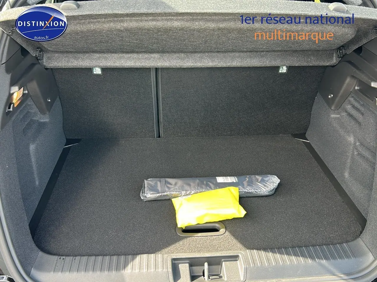 Coffre ouvert vu de l'arrière d'un Renault Captur noir Étoile 2025, avec tapis noir et objets emballés à l'intérieur.