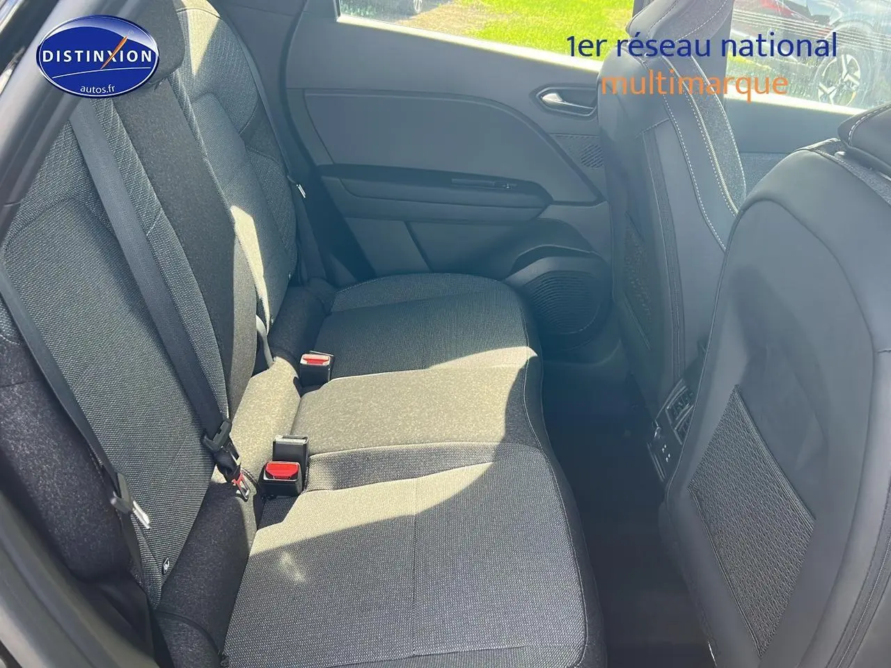 Vue intérieure arrière côté gauche du Renault Captur 2025, sièges tissu gris foncé avec ceintures visibles.