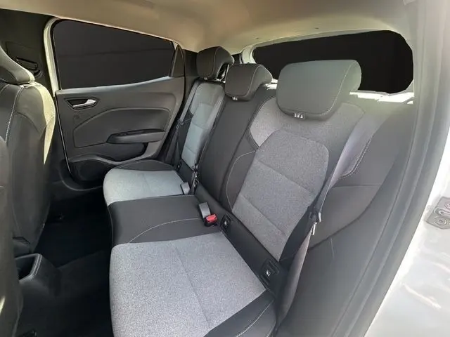 Vue intérieure côté arrière droit de la Renault Clio blanche 2025, montrant la banquette arrière bi-ton gris et noir avec appuie-têtes.
