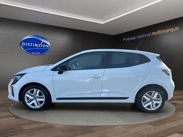 Vue de profil côté gauche d'une Renault Clio blanche Evolution Blue dCi 100 en intérieur avec jantes alliage et rétroviseurs noirs.