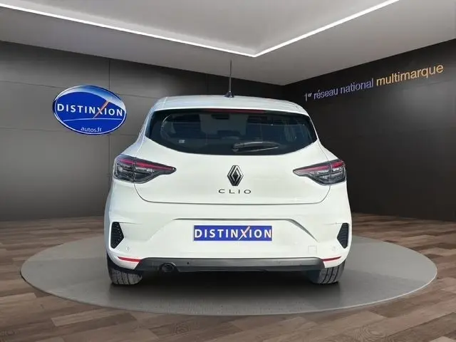 Vue arrière d'une Renault Clio blanche 2025, avec feux LED et logo distinctif sur fond intérieur showroom.