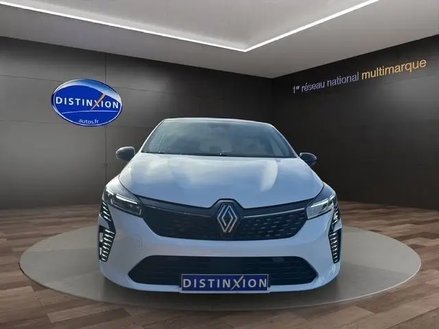 Vue frontale d'une Renault Clio Evolution Blue dCi 100 blanche, avec calandre noire et feux LED distinctifs allumés.
