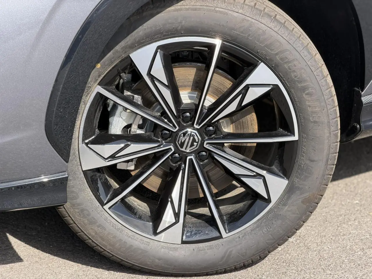 Gros plan sur la jante alliage 19'' noire et argentée du MG MOTOR EHS gris 2026, avec logo MG au centre.