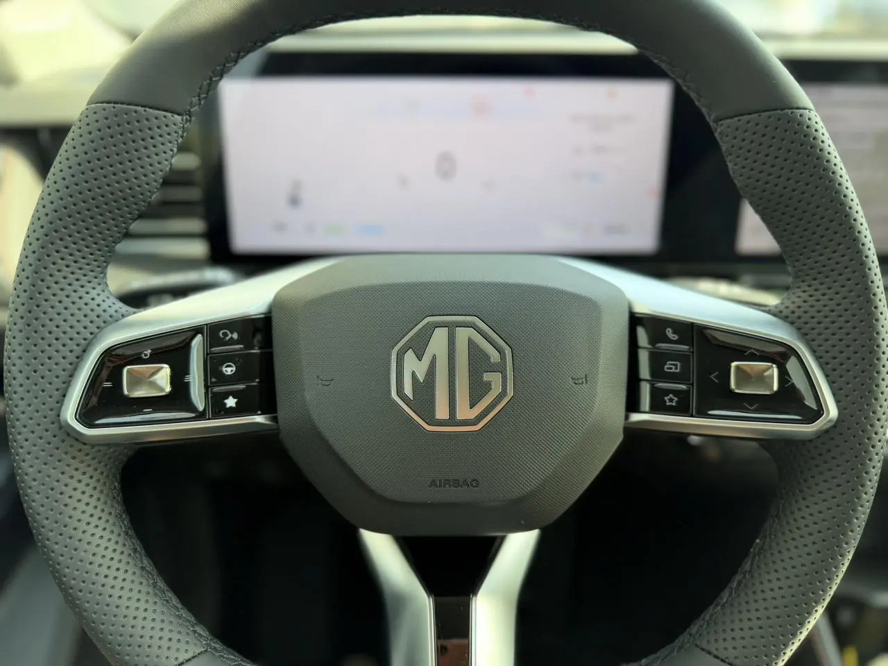 Volant noir perforé du MG Motor EHS 1.5 Hybrid+ 224 Luxury avec logo MG central et commandes intégrées.