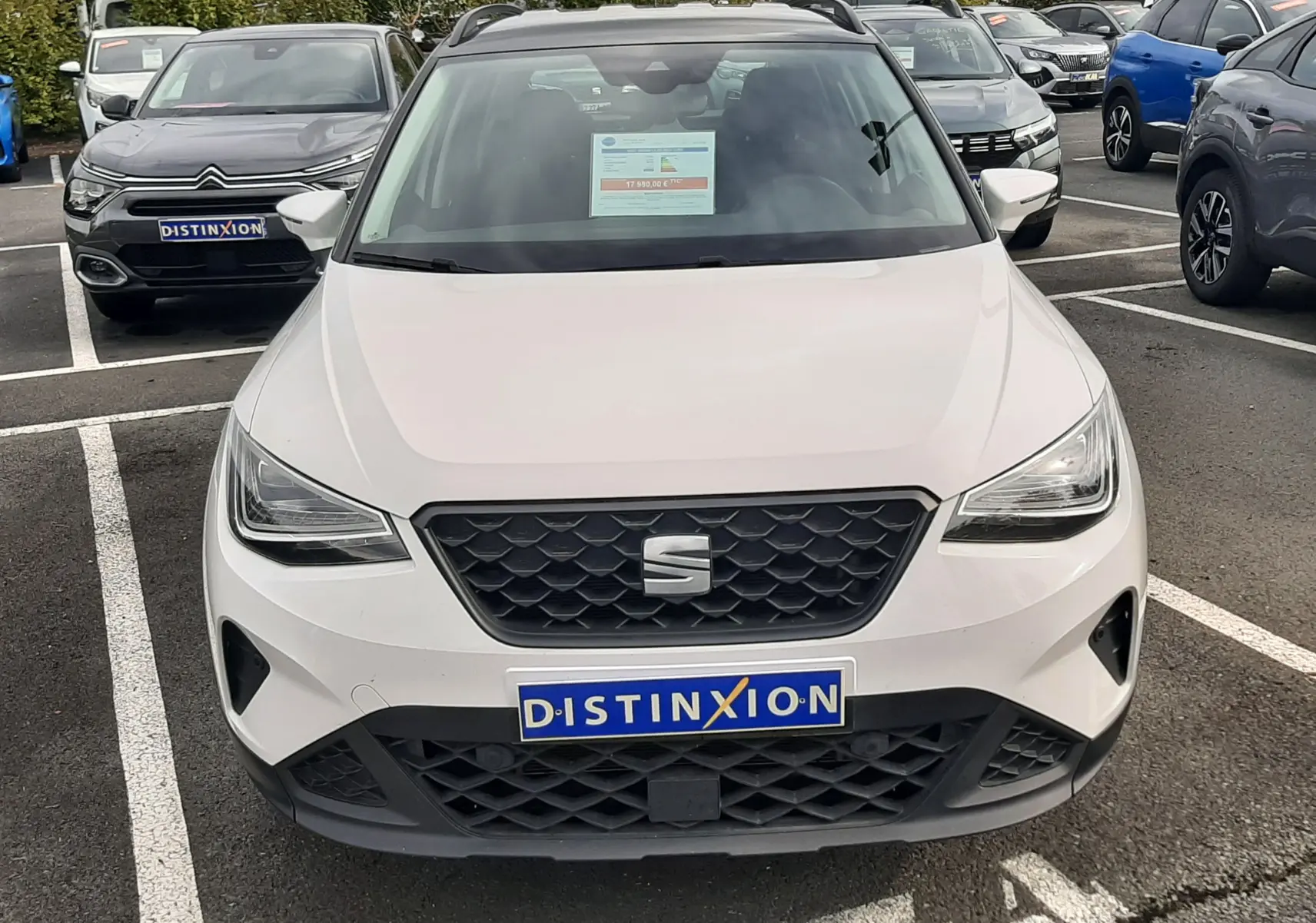 Vue avant d'un SEAT Arona blanc à toit noir, avec calandre noire et plaque d'immatriculation Distinxion visible.