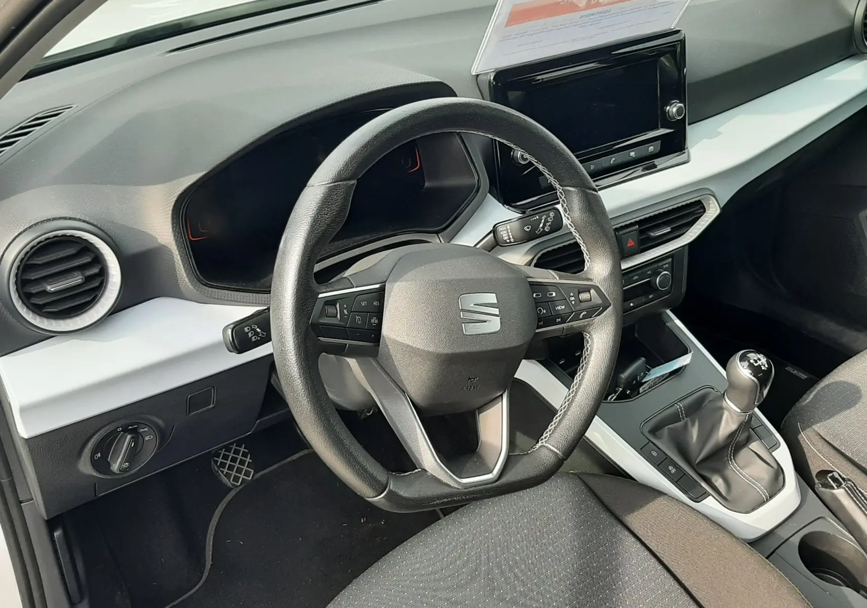 Vue intérieure du poste de conduite de la SEAT Arona 2024, volant multifonction et levier de vitesse manuel visibles.