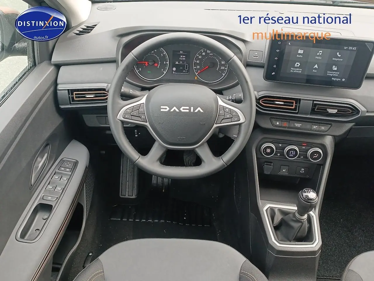 Vue intérieure centrée sur le volant et la console centrale de la Dacia Sandero noire avec boîte manuelle et écran tactile.