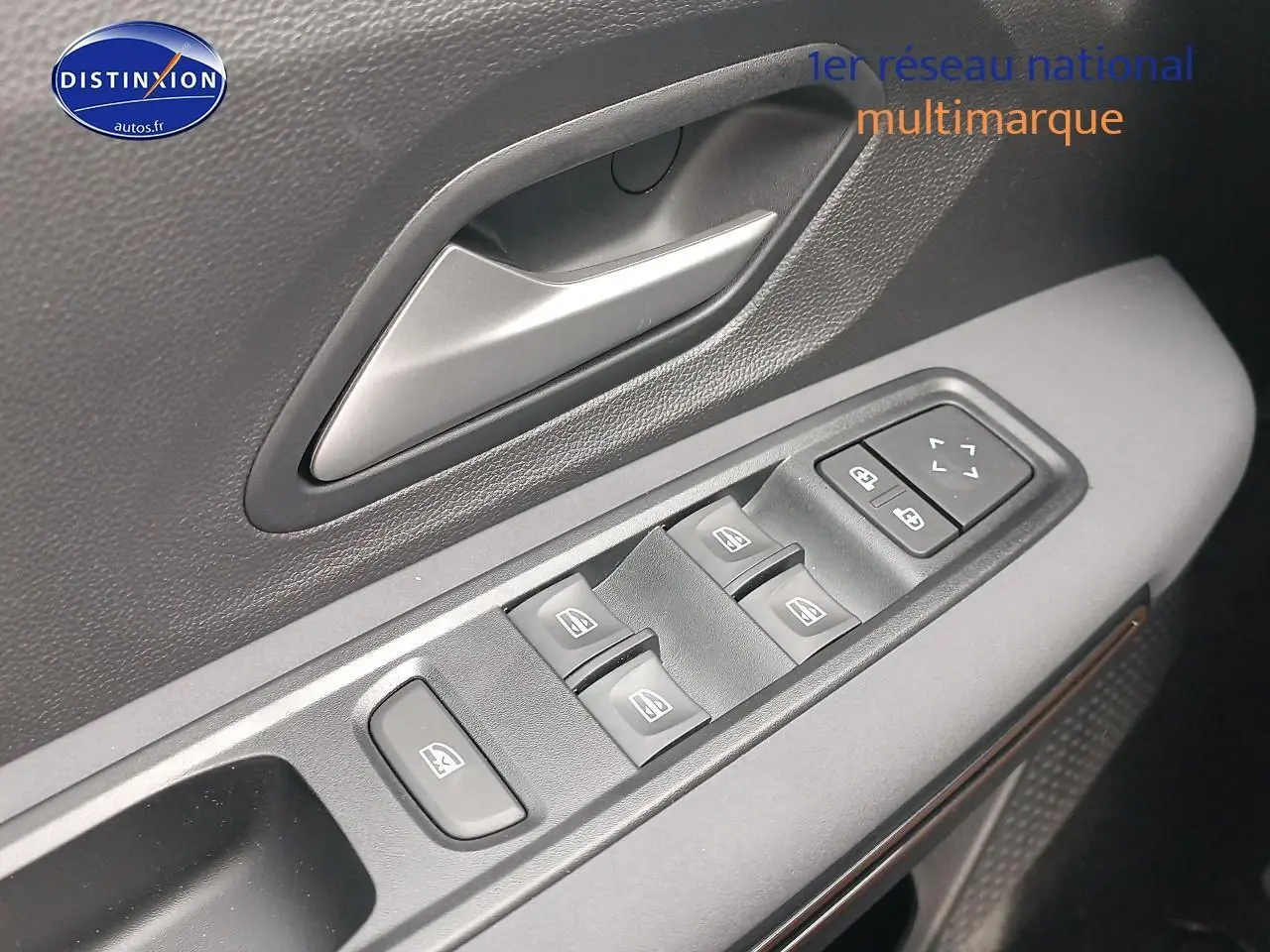 Gros plan sur la commande des vitres électriques et la poignée intérieure côté gauche d'une Dacia Sandero noire 2025.