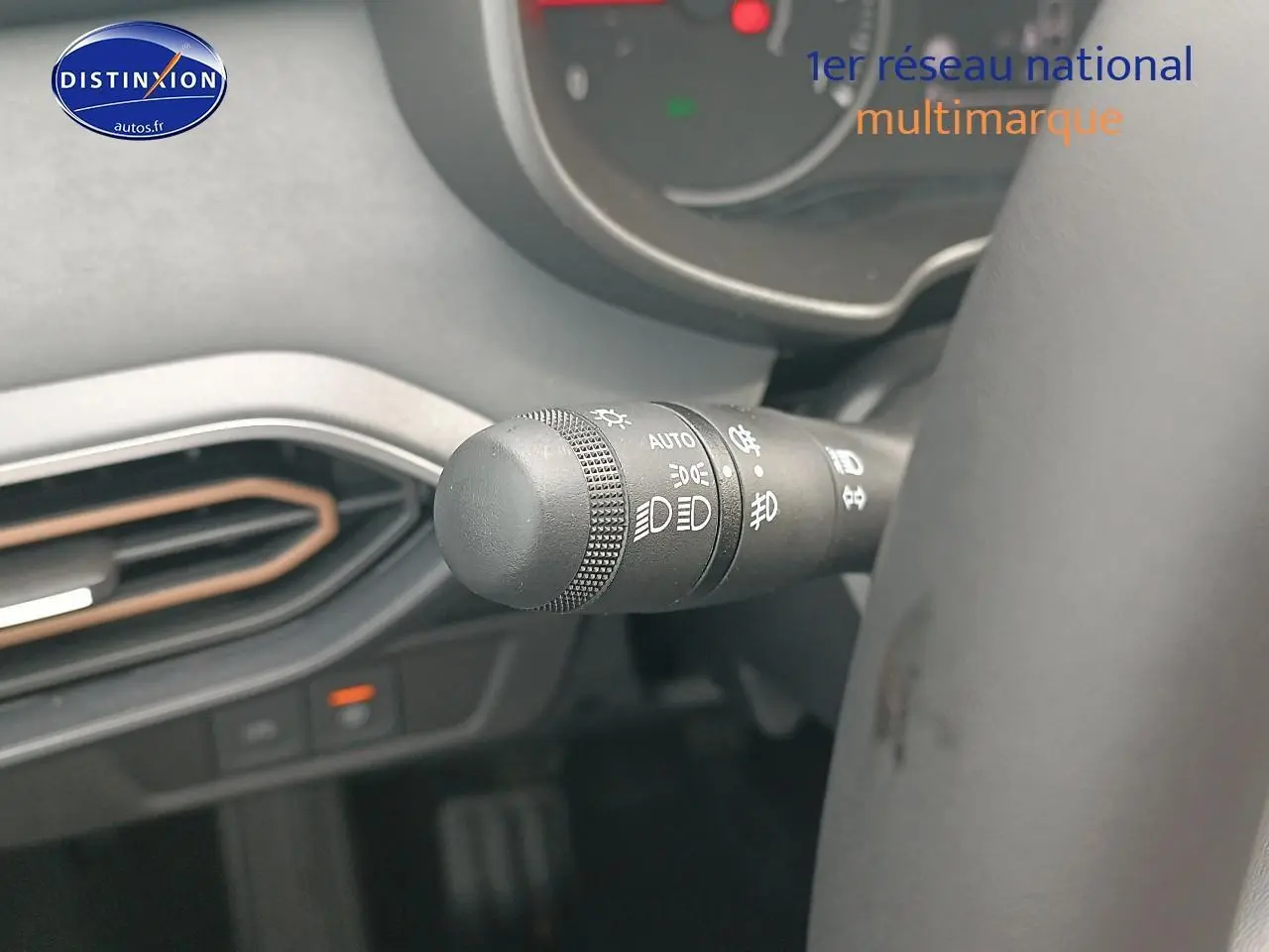 Gros plan sur la commande des phares à gauche du volant dans l’habitacle noir du Dacia Sandero 2025.