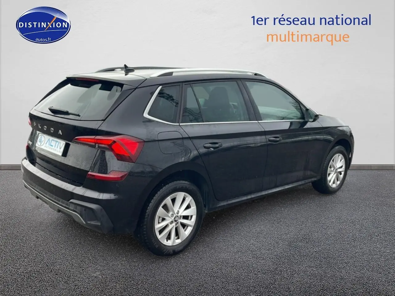 Vue 3/4 arrière droite d'un Skoda Kamiq noir avec jantes alu et barres de toit visibles.