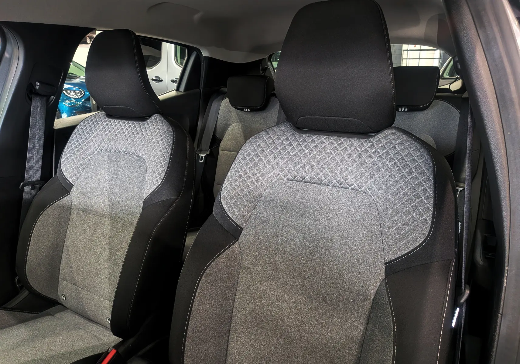 Vue intérieure des sièges avant en tissu gris clair et noir de la Renault Clio V TCe 90 CH Evolution 2024.