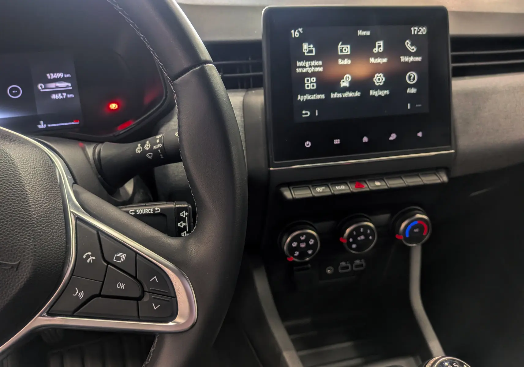 Vue intérieure centrée sur le volant et l'écran tactile de la Renault Clio V TCe 90 Gris Schiste, avec commandes au volant et boîte manuelle.