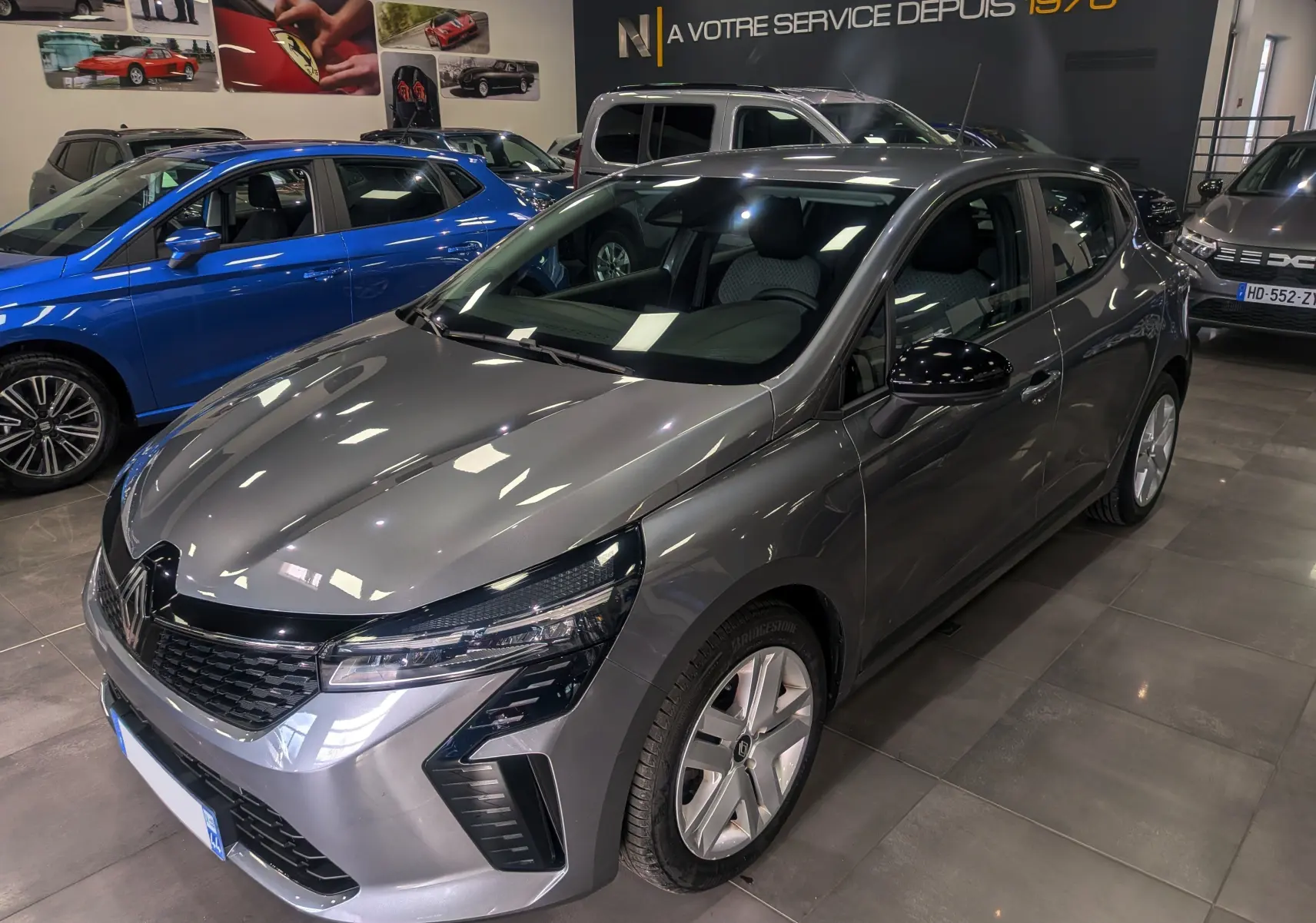 Renault Clio V TCe 90 Evolution gris schiste vue 3/4 avant droit en intérieur, avec phares LED distinctifs.