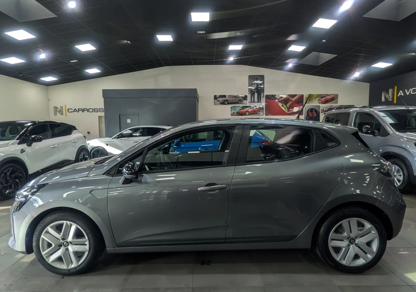 Profil latéral droit de la Renault Clio V TCe 90 Evolution gris schiste, avec jantes alliage et poignées intégrées au montant arrière.