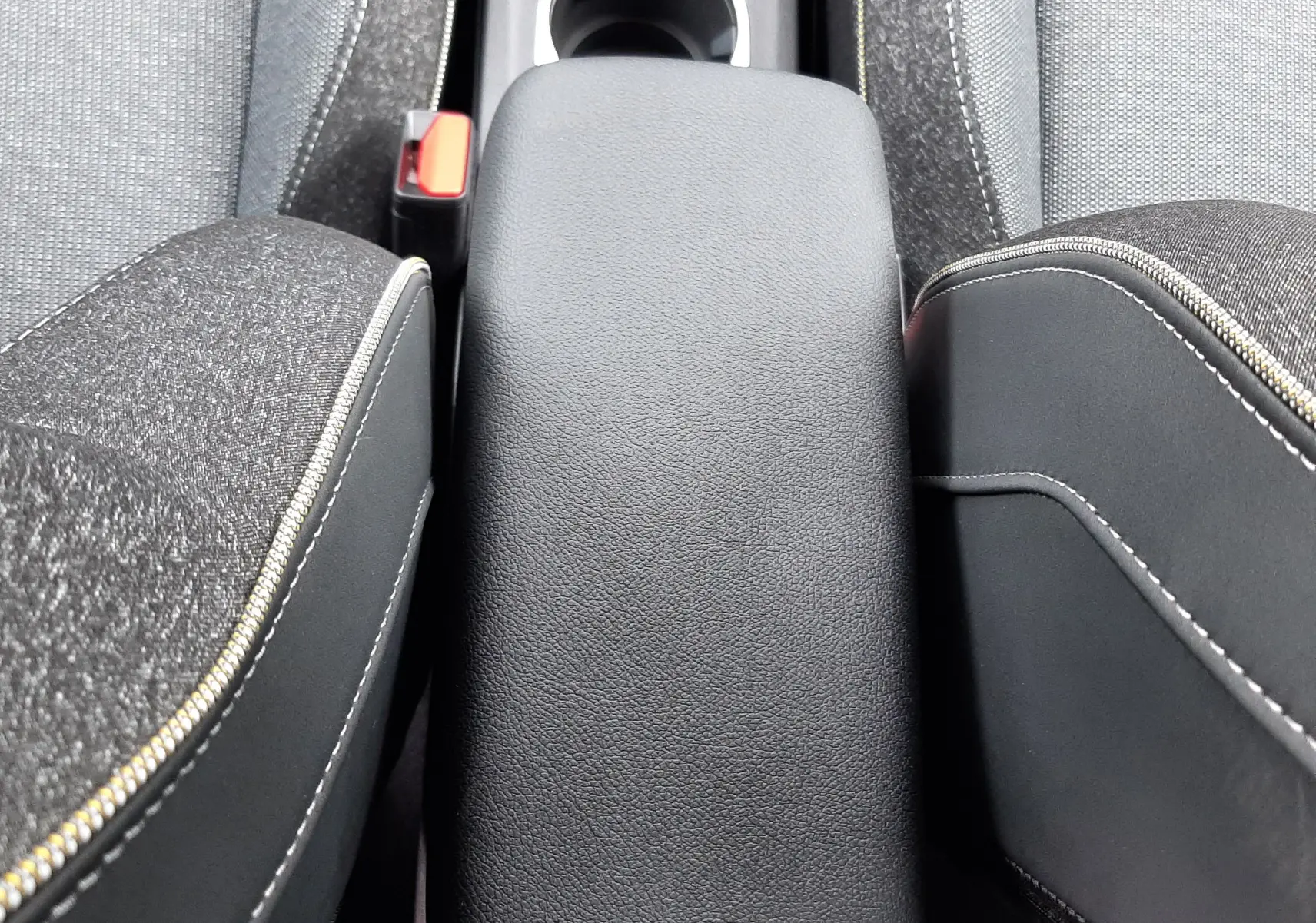 Vue rapprochée de l'accoudoir central noir entre les sièges tissu gris du Renault Captur E-Tech Full Hybrid 160ch Techno.