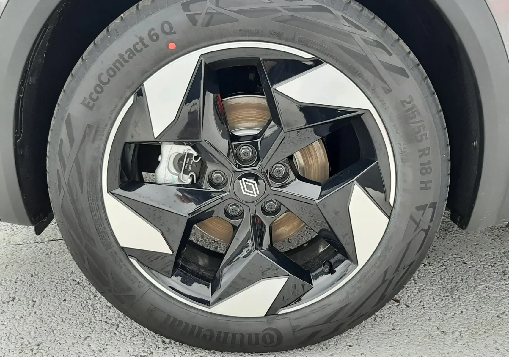 Gros plan sur la roue avant droite du Renault Captur E-Tech gris Cassiopée, jante alliage noire et argentée à design étoilé.