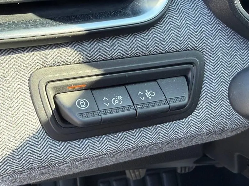 Gros plan sur les commandes de réglage des feux et du tableau de bord de la Renault Clio 1.0 TCe 90ch Techno 2025, tissu gris à chevrons.