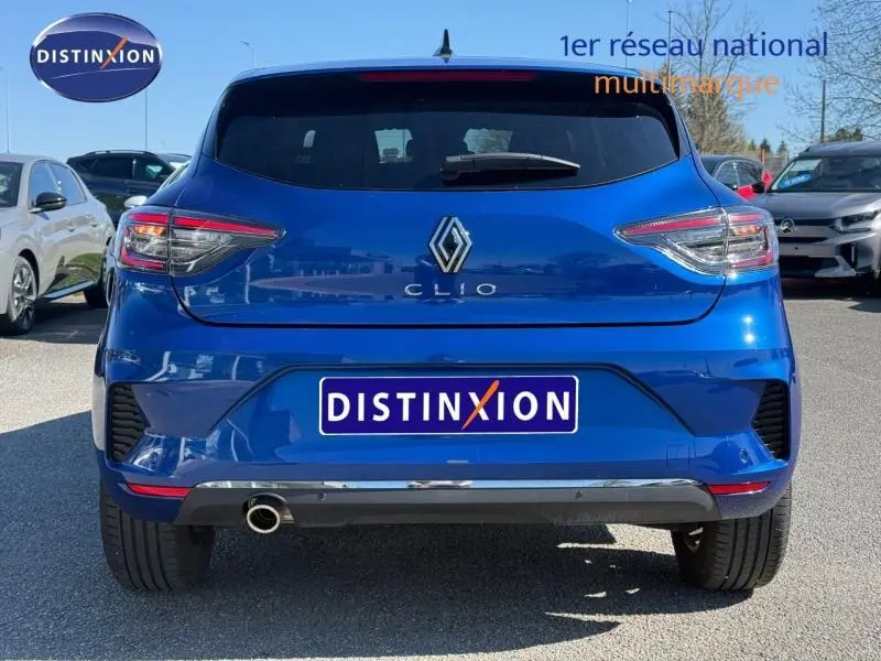 Vue arrière d'une Renault Clio 2025 Bleu Iron avec logo et feux arrière distinctifs, sur parking extérieur ensoleillé.