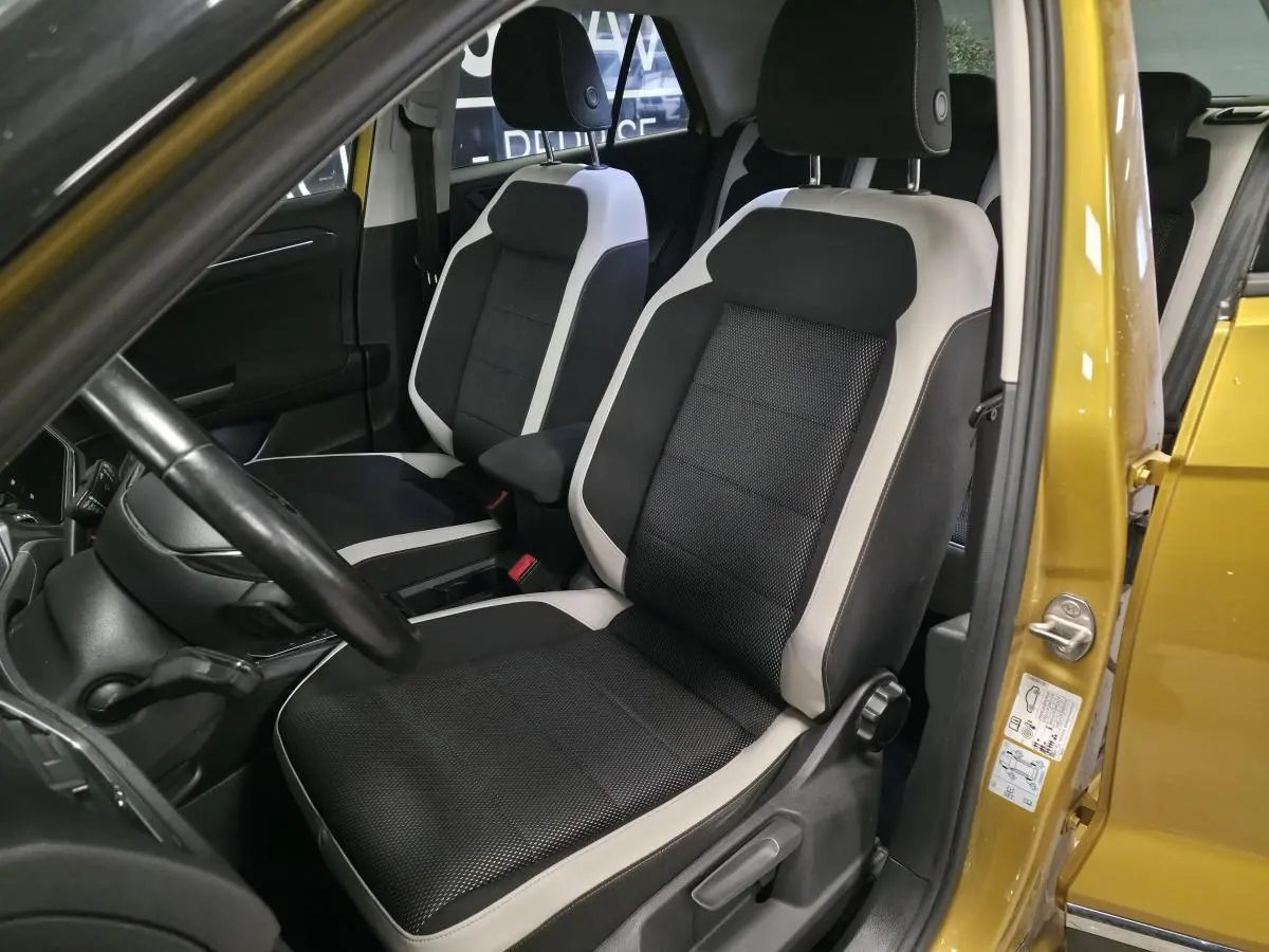 Vue intérieure côté conducteur du Volkswagen T-Roc jaune 2021, sièges tissu noir et beige avec volant cuir.