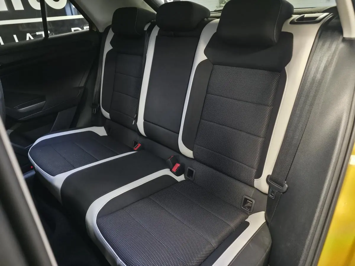 Vue intérieure de la banquette arrière noire et grise du Volkswagen T-Roc jaune 2021, avec ceintures de sécurité visibles.