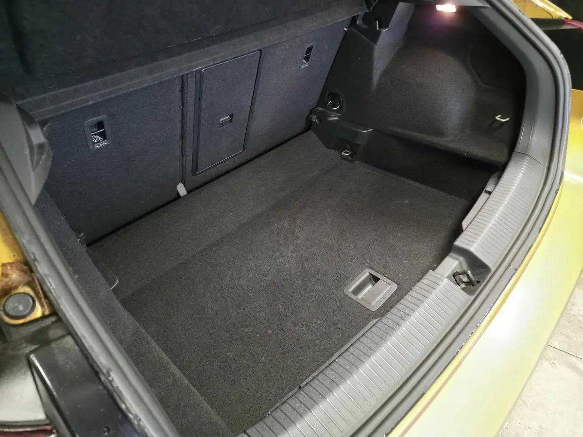 Coffre ouvert du Volkswagen T-Roc jaune, montrant l'espace de rangement intérieur et les finitions en tissu noir.