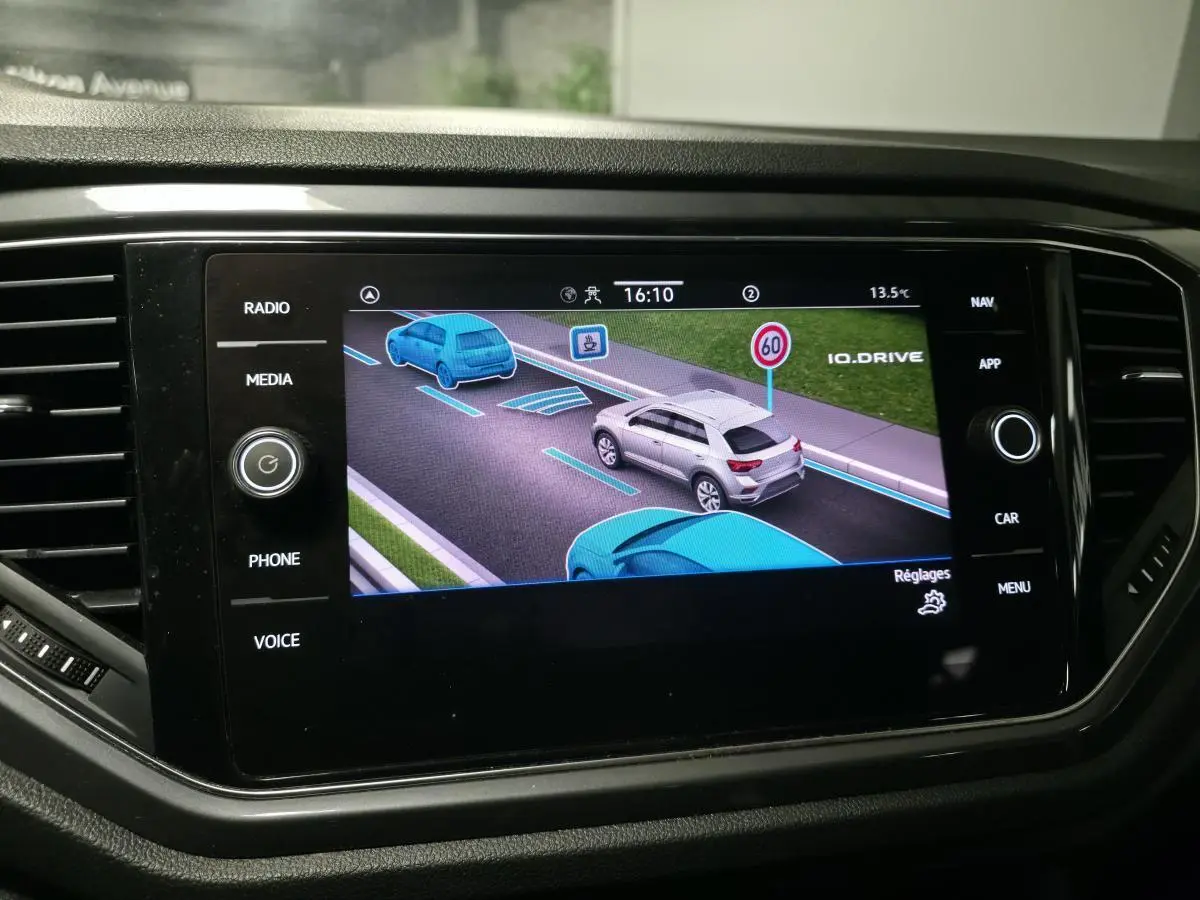 Écran tactile intérieur montrant l'assistance à la conduite avec véhicules en bleu et gris sur route virtuelle.