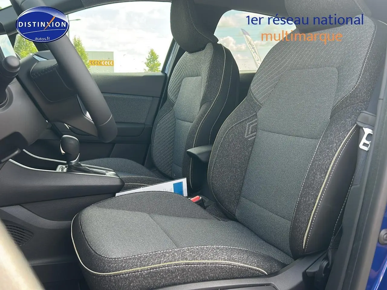 Vue intérieure côté conducteur du Renault Captur 1.6 e-tech hybride 2025 avec sièges tissu gris et surpiqûres contrastées.