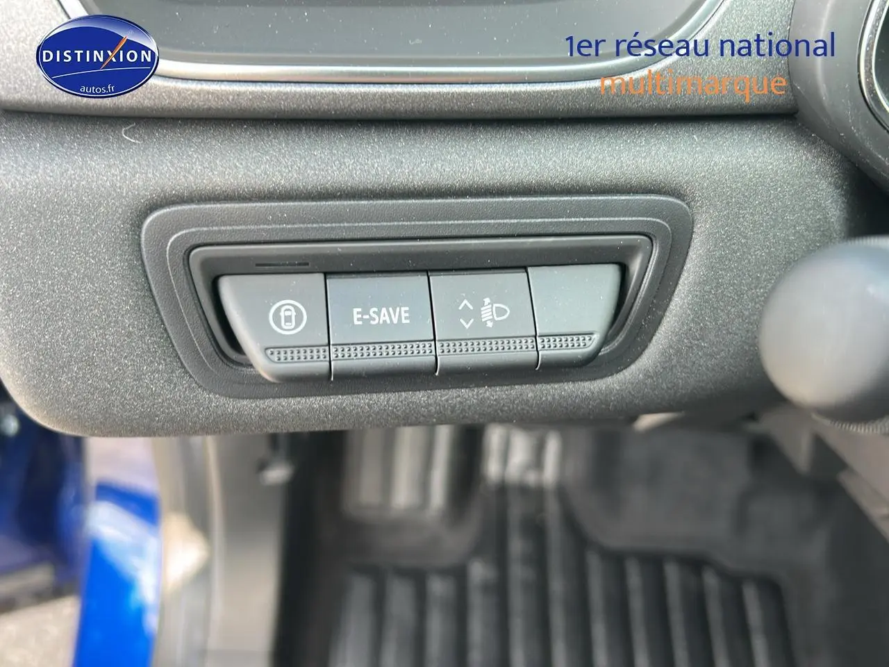 Gros plan sur les commandes E-SAVE et réglage des phares du tableau de bord d’un Renault Captur Bleu Iron.