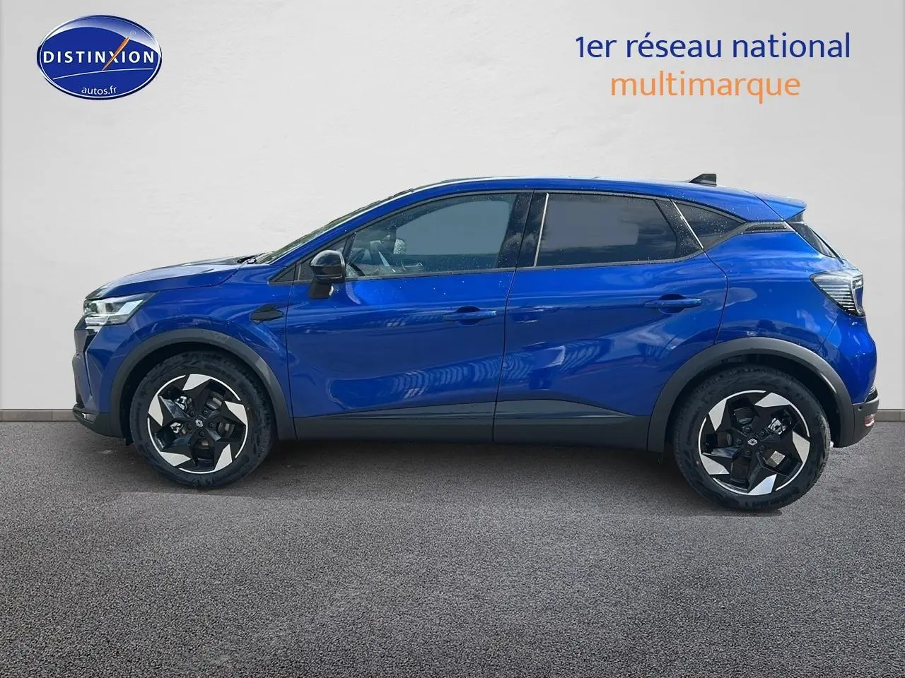 Profil latéral droit d'un Renault Captur 1.6 e-tech hybride 145 techno bleu iron avec jantes alu et vitres surteintées.