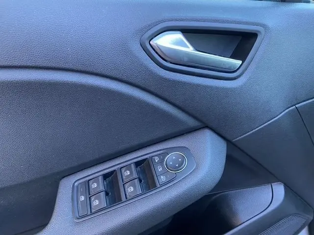 Vue rapprochée de la porte avant gauche de la Renault Clio 2024 gris foncé, avec commandes des vitres et poignée intérieure.