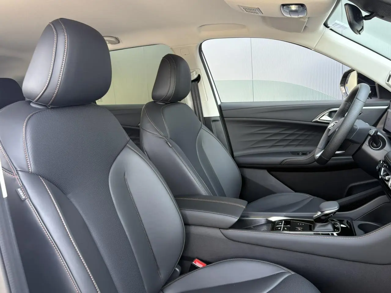Vue intérieure côté droit des sièges avant noirs en simili cuir du MG MOTOR EHS 1.5 Hybrid+ 224 Luxury 2026.