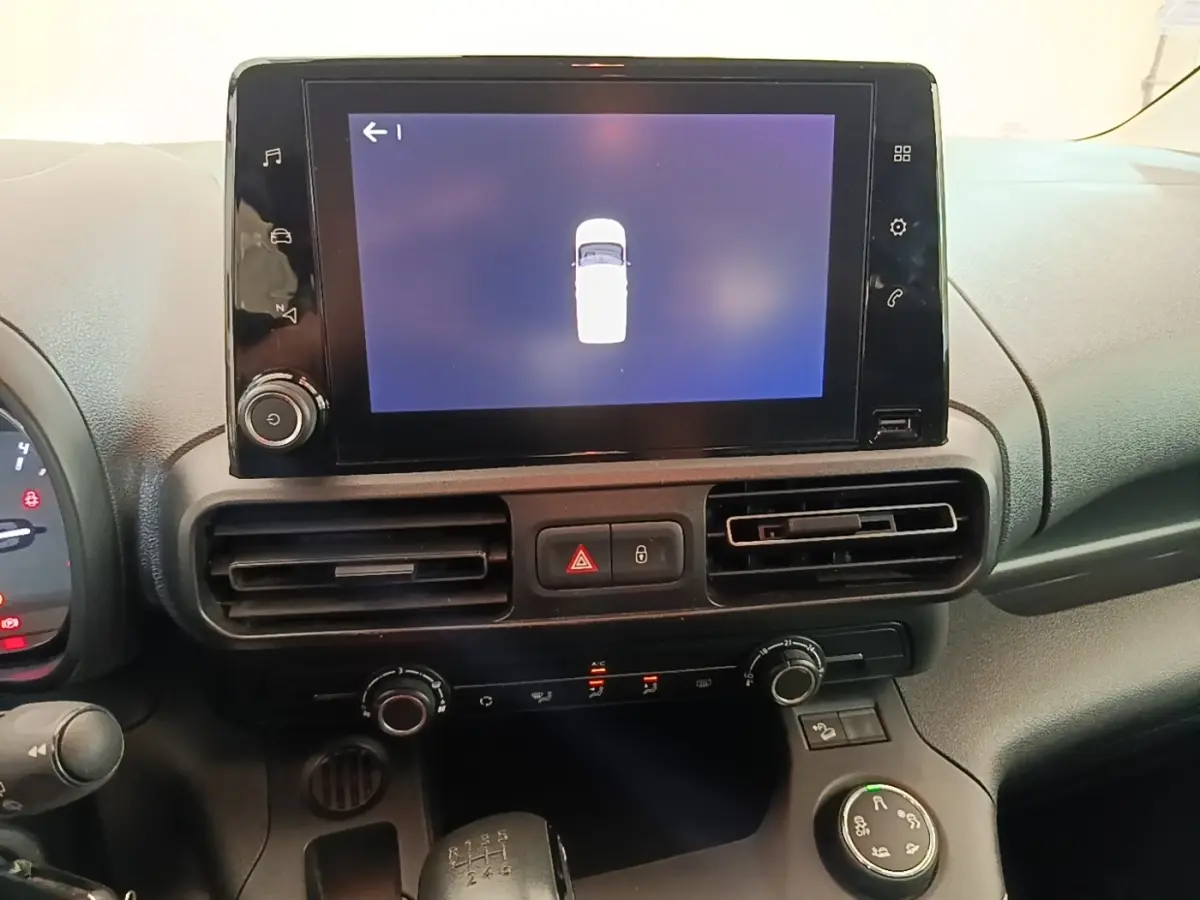 Vue rapprochée du tableau de bord du Citroën Berlingo blanc 2022, écran tactile central et commandes climatisation.