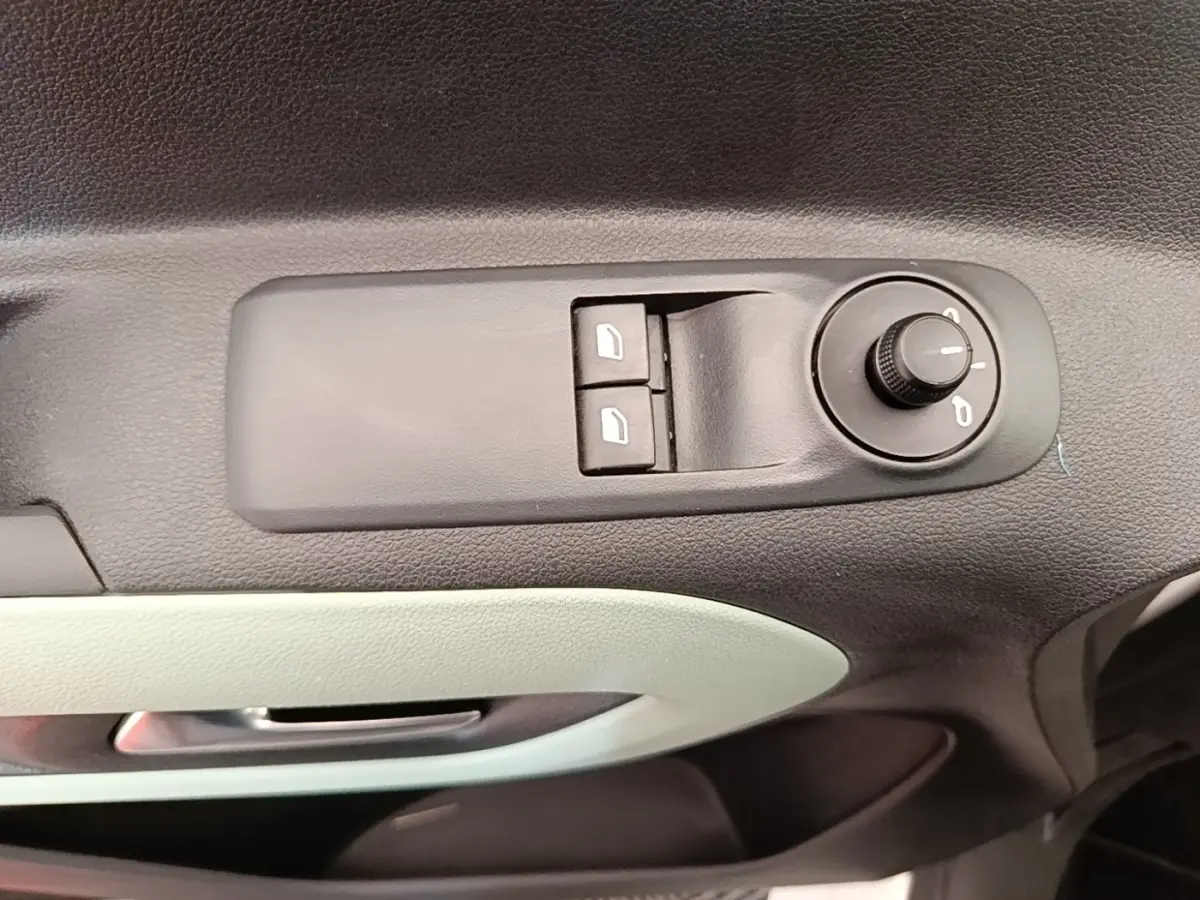 Détail des commandes de réglage des rétroviseurs et des vitres sur la porte avant gauche d’un Citroën Berlingo blanc.