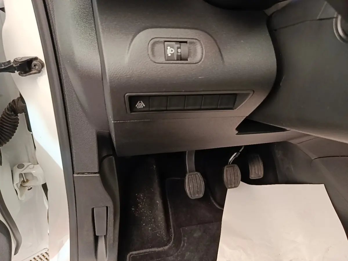 Vue intérieure côté conducteur du Citroën Berlingo blanc 2022, montrant les pédales et commandes sous le tableau de bord.