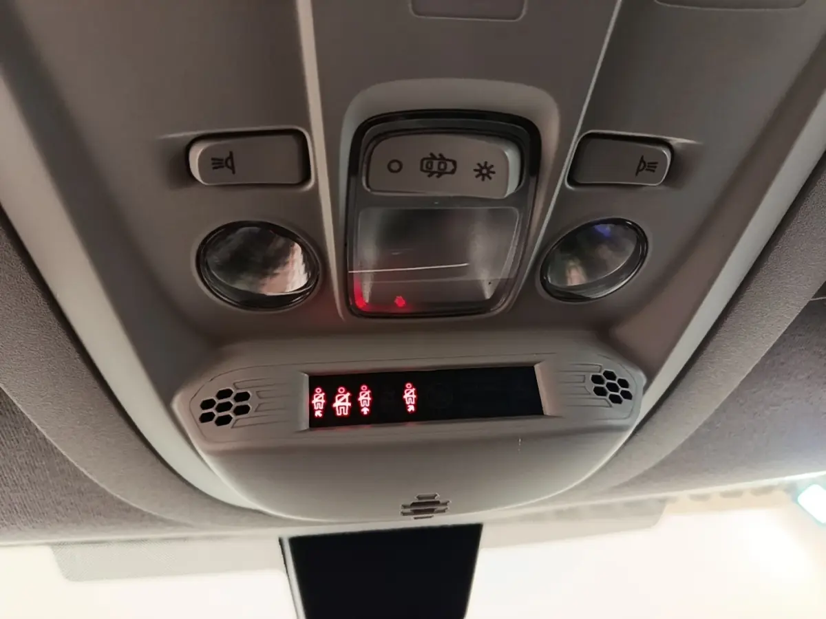 Vue intérieure en plongée du plafonnier gris clair du Citroën Berlingo blanc avec éclairages et indicateurs rouges allumés.