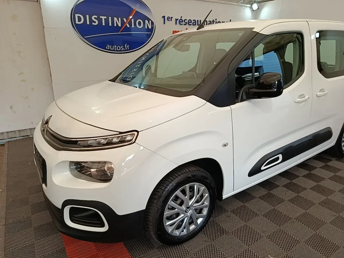 Vue 3/4 avant droite d'un Citroën Berlingo blanc avec protections latérales noires et jantes alliage.