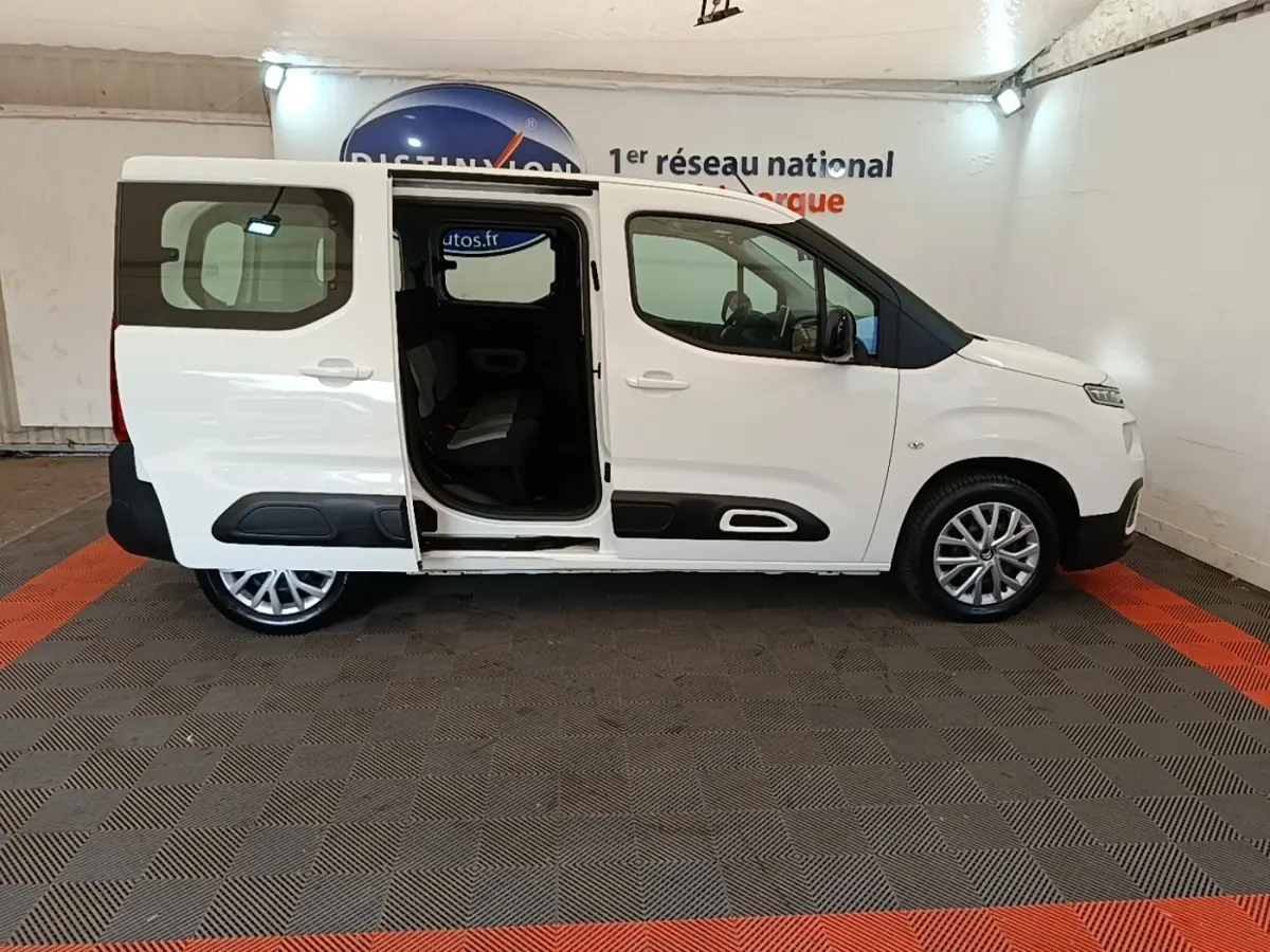 Profil droit d’un Citroën Berlingo blanc 2022 avec porte coulissante arrière ouverte en intérieur showroom.