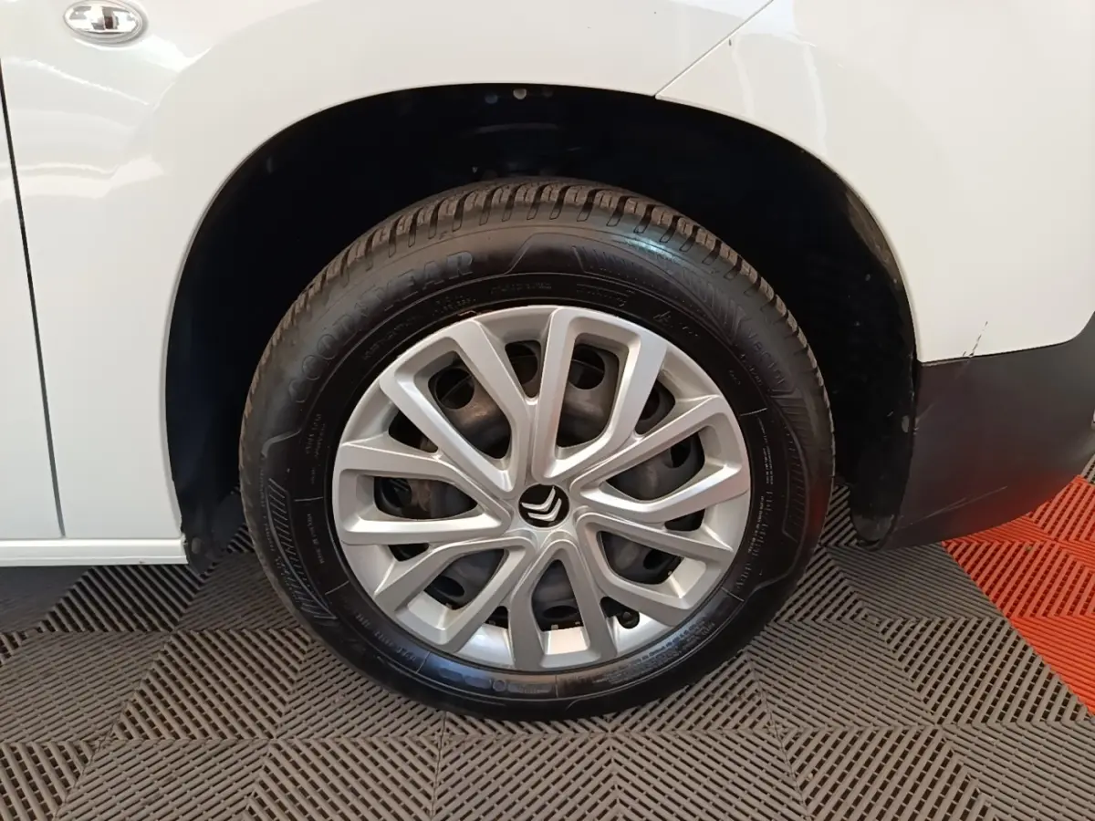 Gros plan sur la roue avant gauche blanche d’un Citroën Berlingo avec jante argentée au design moderne.