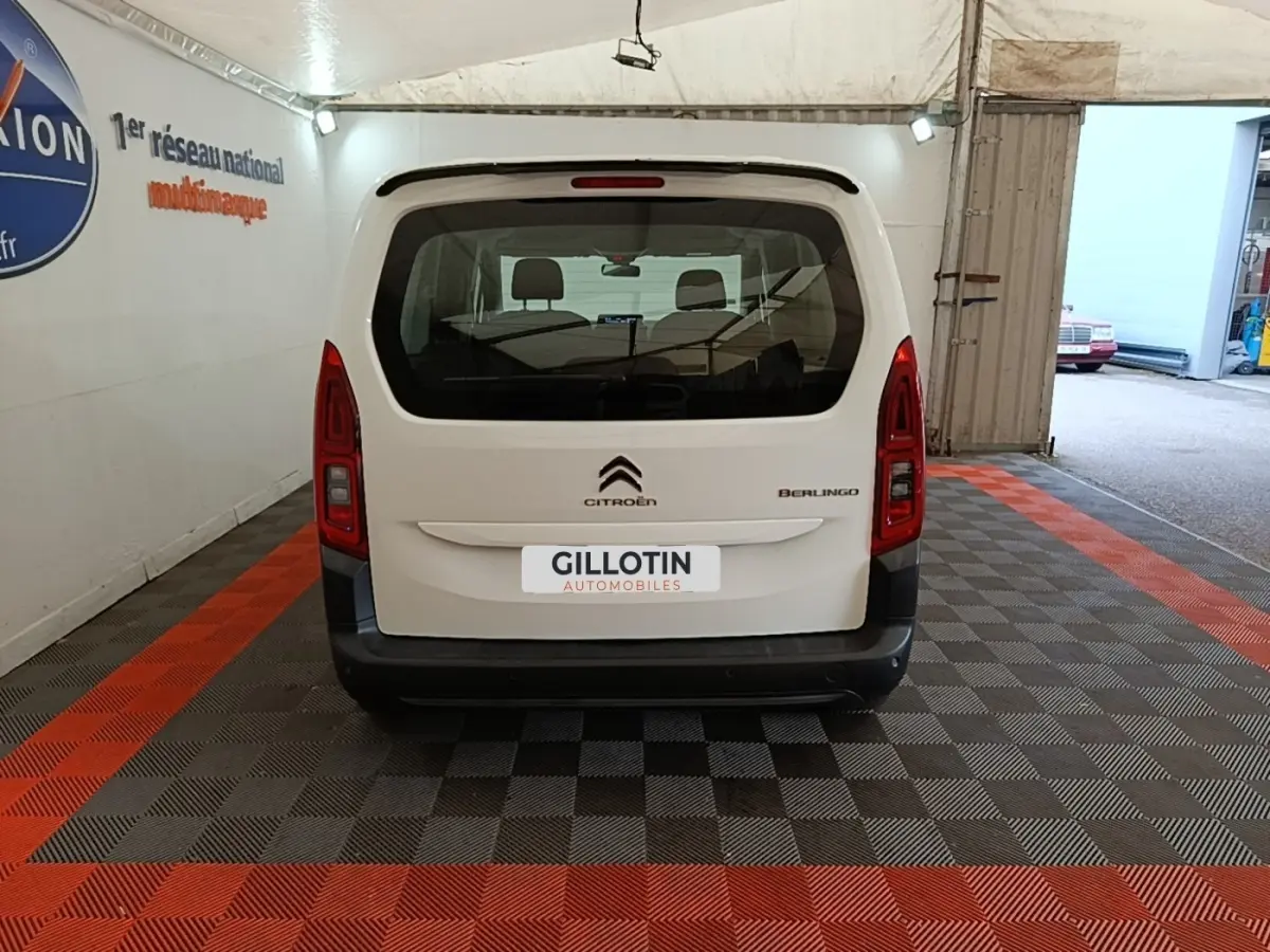 Vue arrière d'un Citroën Berlingo blanc garé en intérieur avec logo et feux verticaux rouges visibles.