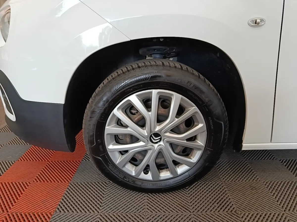 Gros plan sur la roue avant droite d’un Citroën Berlingo blanc avec jante en alliage et logo Citroën visible.