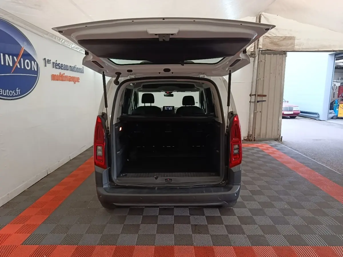 Vue arrière d'un Citroën Berlingo blanc 2022 avec hayon ouvert montrant le coffre vide dans un garage.