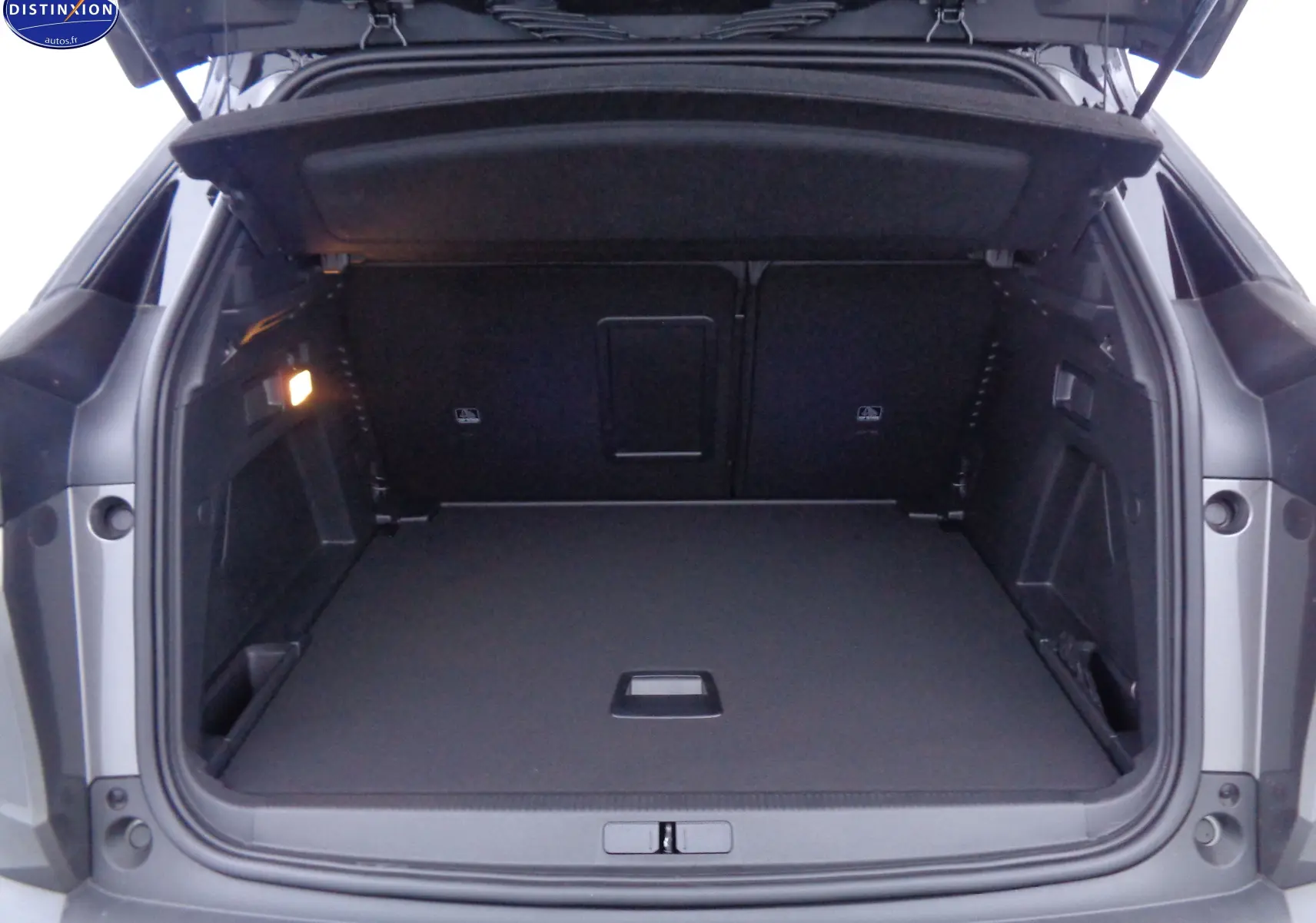 Coffre ouvert vu de l'arrière du Peugeot 3008 gris platinium, montrant un espace de chargement spacieux et bien éclairé.